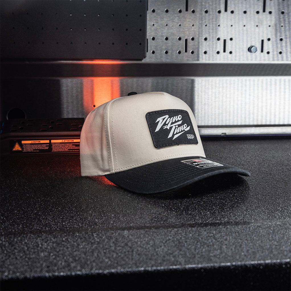 Adjustable snapback two toned black and cream hat with black dyno time woven patch. 