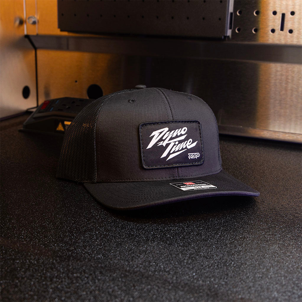 Black adjustable 112 richardson snapback hat with custome woven dyno time patch with white text. 